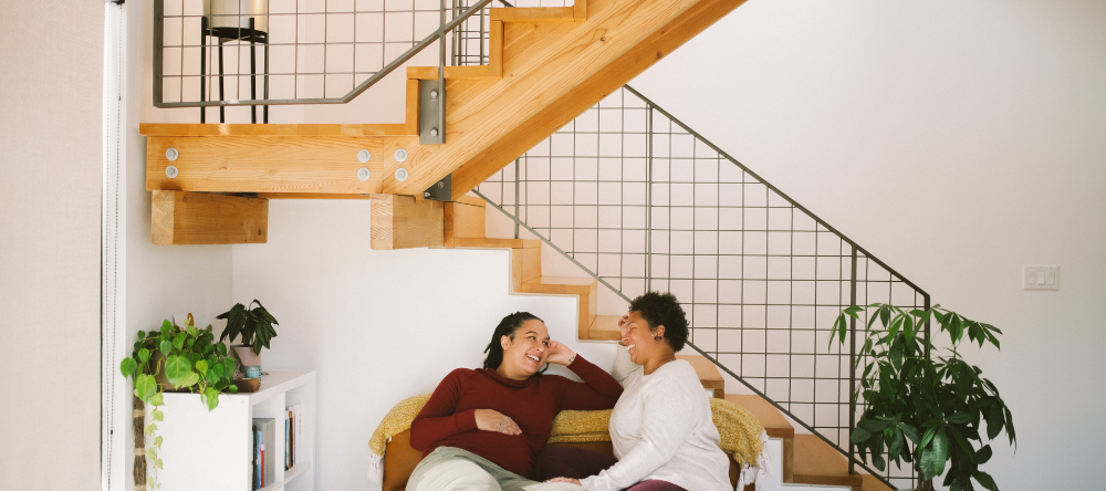 A couple sitting on the stairs in their home.